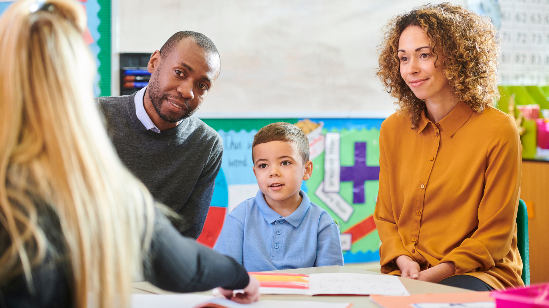 Parents and student meeting with a teacher in a classroom